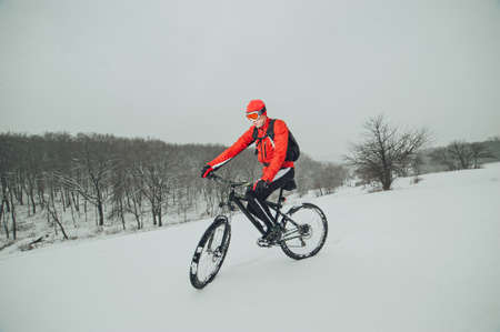 Extreme cyclist rides in the winter snowy forestの写真素材