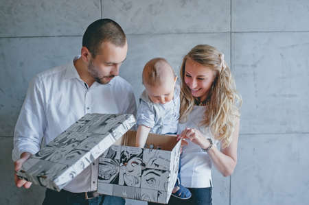 young family mother, father, son, opens a giftの写真素材