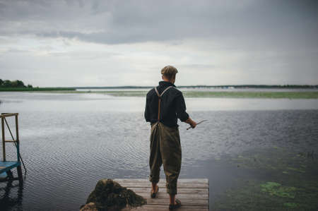 man fisherman catches a fish in the river from the bridgeの写真素材