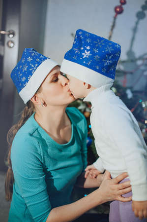 Mother kisses the child against the background of the Christmas treeの写真素材