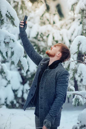 stylish man with a cell phone in the winter forestの写真素材