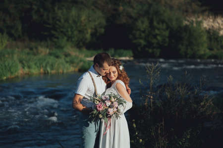the bride and groom on the background of a mountain streamの写真素材