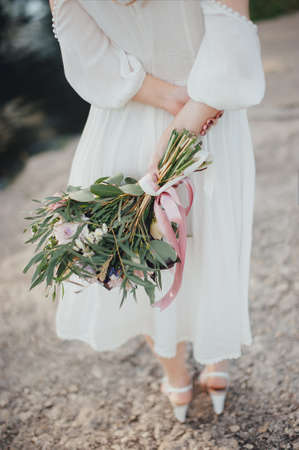The bride with a bouquet on beautiful large lake background at sunset. Rustic Weddingの写真素材