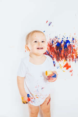Little baby boy covered in paint for paintingの写真素材