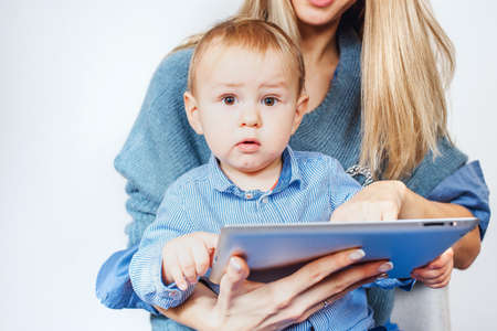 Child with tablet smiles in his mothers armsの写真素材