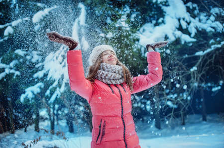 Girl in mittens throws snow in the winter forestの写真素材