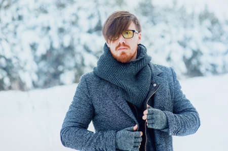 stylish man with a beard in snowy winter forestの写真素材