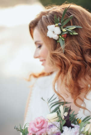 Beautiful bride with a bouquet of different flowers on background lake. Rustic Weddingの写真素材