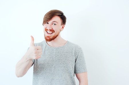 Bearded man showing thumbs up on a light background. Successの写真素材