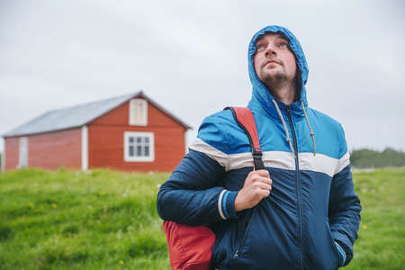 Tourist with a backpack in  blue jacket on  background of green fieldの写真素材