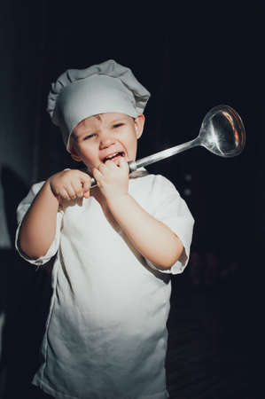 Child chef with a ladle on a black backgroundの写真素材