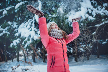 Girl in mittens throws snow in the winter forestの写真素材