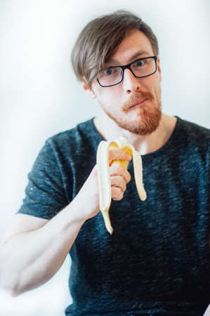 man with a beard wearing glasses eating bananaの写真素材