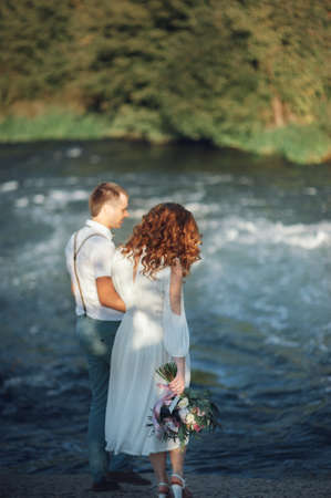the bride and groom on the background of a mountain streamの写真素材
