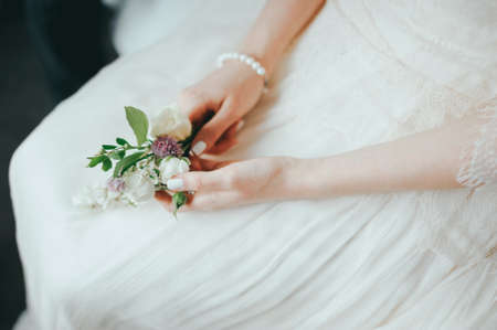 beautiful and delicate wedding boutonniere for the groom in brides handsの写真素材