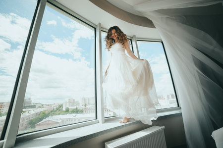 Beautiful stylish bride walks on the windowsill