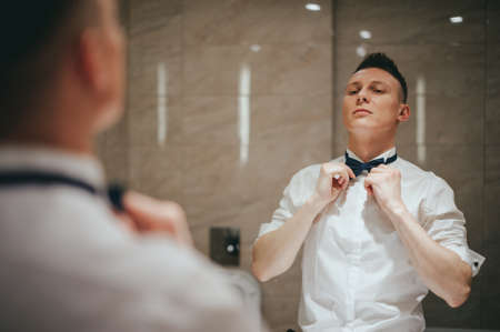 Wedding preparations of the groom. Positioning in front of the mirrorの写真素材