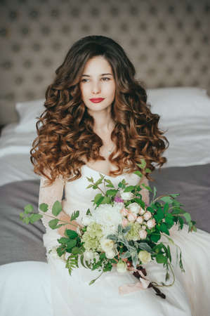 Luxury stylish bride sitting on the bed and looking at the cameraの写真素材