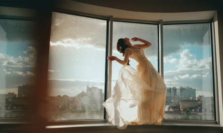The bride posing against the window. Flying dressの写真素材