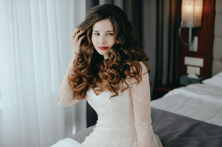 Luxury stylish bride sitting on the bed and looking at the cameraの写真素材