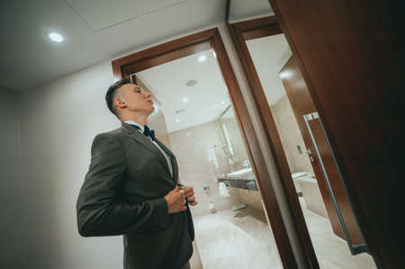The groom in front of the mirror. Wedding preparationsの写真素材