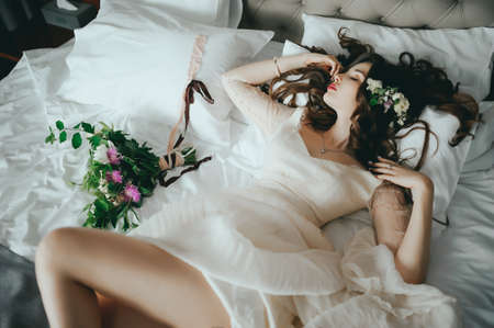 A beautiful stylish bride lies on the bed. Fancy Hairstyleの写真素材