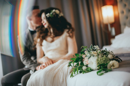 Wedding shot of stylish bride and groom sitting on bedの写真素材