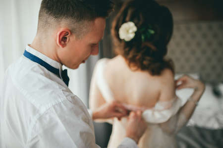 The groom dresses the bride. Wedding preparationsの写真素材