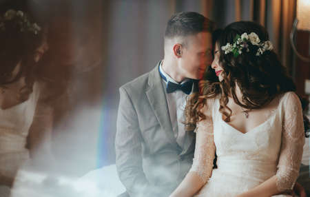 Wedding shot of stylish bride and groom sitting on bedの写真素材