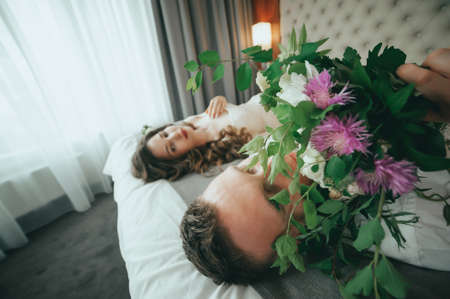Stylish bride and groom are lying on the bedの写真素材