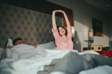 Fashion photo of two young beautiful lovers relax at the hotel on a bed,they are smilingの写真素材