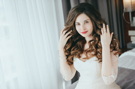 Luxury stylish bride sitting on the bed and looking at the camera