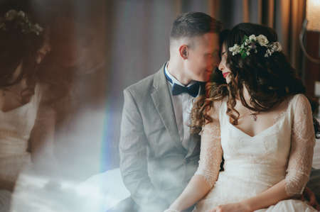 Wedding shot of stylish bride and groom sitting on bedの写真素材