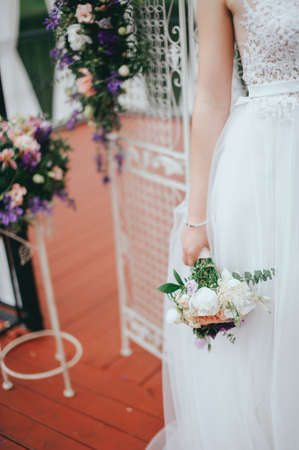 Stylish beautiful bride holds a wedding bouquet in handsの写真素材