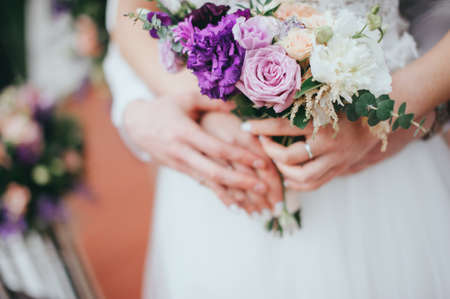Stylish beautiful bride holds a wedding bouquet in handsの写真素材