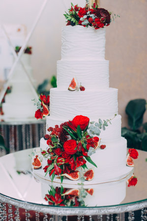 Wedding cake with red fresh flowers and fresh fruits