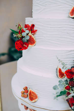 Wedding cake with red fresh flowers and fresh fruitsの写真素材