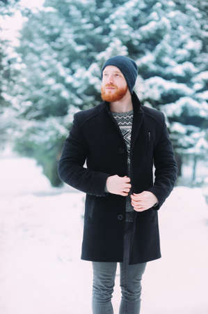 A man with a beard and mustache in a hood with fur on a snowy forestの写真素材