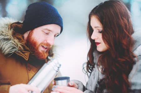 guy and girl drinking tea in the snowy forestの写真素材