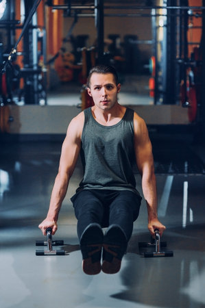 Athletic man which shakes the press on bars near the window in gym
