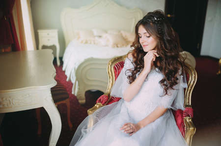 the bride posing on a red chair in the hotelの写真素材