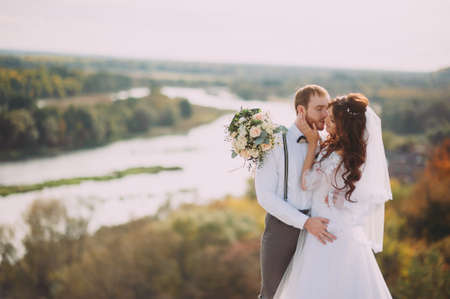 Stylish bride and groom posing on the background of the river. Wedding coupleの写真素材