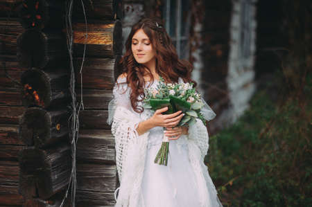 portrait of a beautiful bride against the background of a wooden houseの写真素材