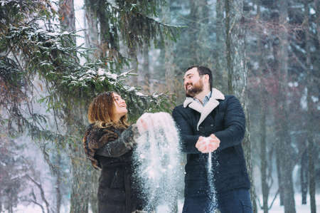 A young and beautiful couple is walking in the winter park, hugging and having fun. A Valentines Day and love story concept. Winter season.の写真素材