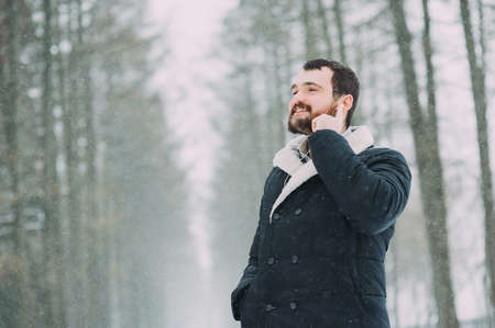 the guy with the beard is listening to music in the snowy forestの写真素材