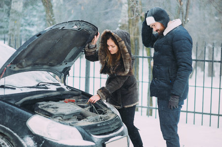 Young woman hitchhiking on a roadside near the broken carの写真素材