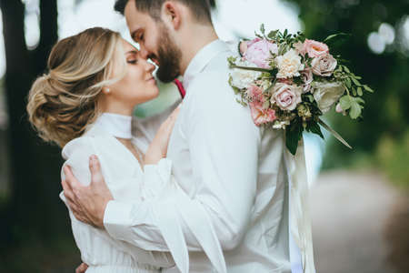 Romantic wedding moment, couple of newlyweds smiling portrait, bride and groom hug while on a walk in the parkの写真素材