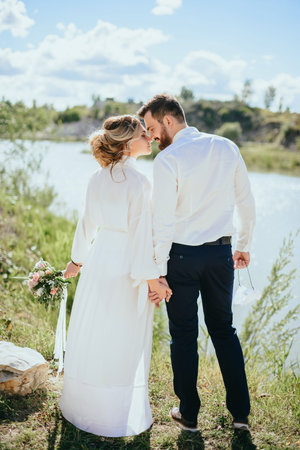 Beautiful wedding couple, bride,groom kissing and posing on the bridge near lakeの写真素材