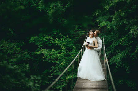 the bride and groom posing on a suspension bridgeの写真素材