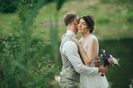 the bride and groom walk on a background of lake. Romantic wedding photo.の写真素材